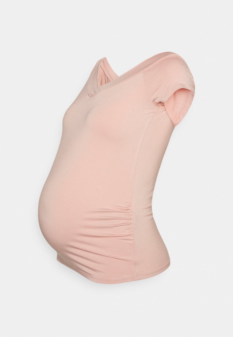 Camiseta de maternidade em tecido leve e elástico de cor rosa claro. Apresenta um decote em V, mangas curtas e um franzido na lateral para um visual ajustado.