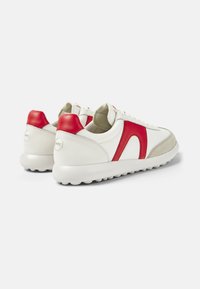 Adidași din piele alba cu accente roșii, detalii din suede bej și o talpă texturată, groasă. Prezentă logo-ul pe toc și un design cu șireturi.