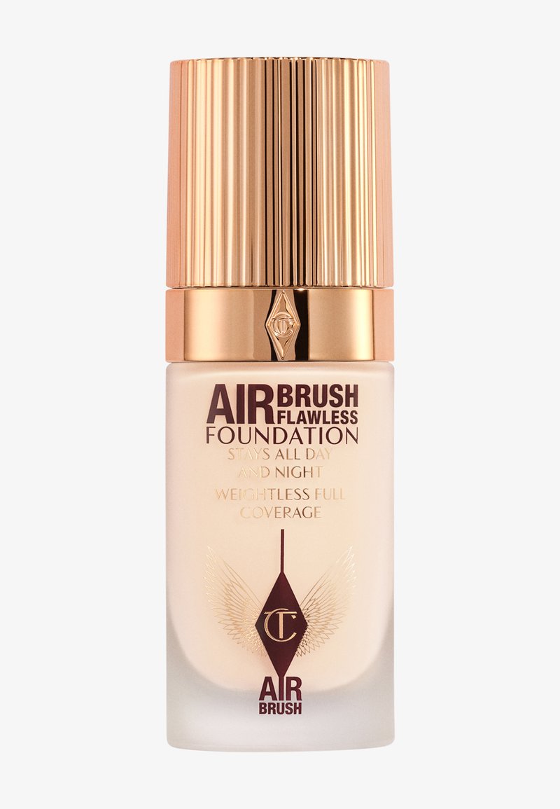 Airbrush Flawless Foundation in a clear glass bottle with a gold ribbed cap. Features embossed logo and printed claims in dark brown.