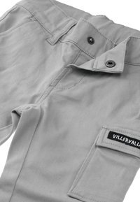 Graue Baumwollhose mit einer Tasche und einem schwarzen Etikett. Der Bund hat Knöpfe und einen Deckel, der eine glatte Textur zeigt.