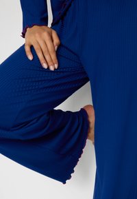 Sinine ribaga k sweatpants komplekt, millel on laienevad varrukad roosa ruffle äärisega ja sobiv disain põlvede ümber.