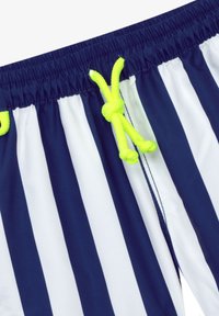 Un maillot de bain rayé bleu marine et blanc avec une taille élastique, doté d'un cordon de serrage jaune fluo pour un ajustement, et en tissu lisse et léger.