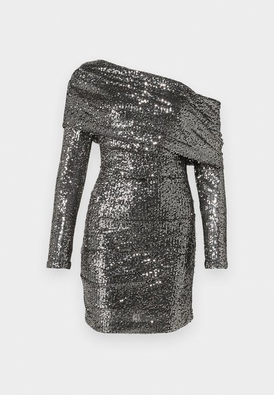 Blizgučiais puošta suknelė su nelygiais pečiais, ilgomis rankovėmis ir aptemptu siluetu. Pagaminta iš sidabrinės spalvos metalinio audinio.