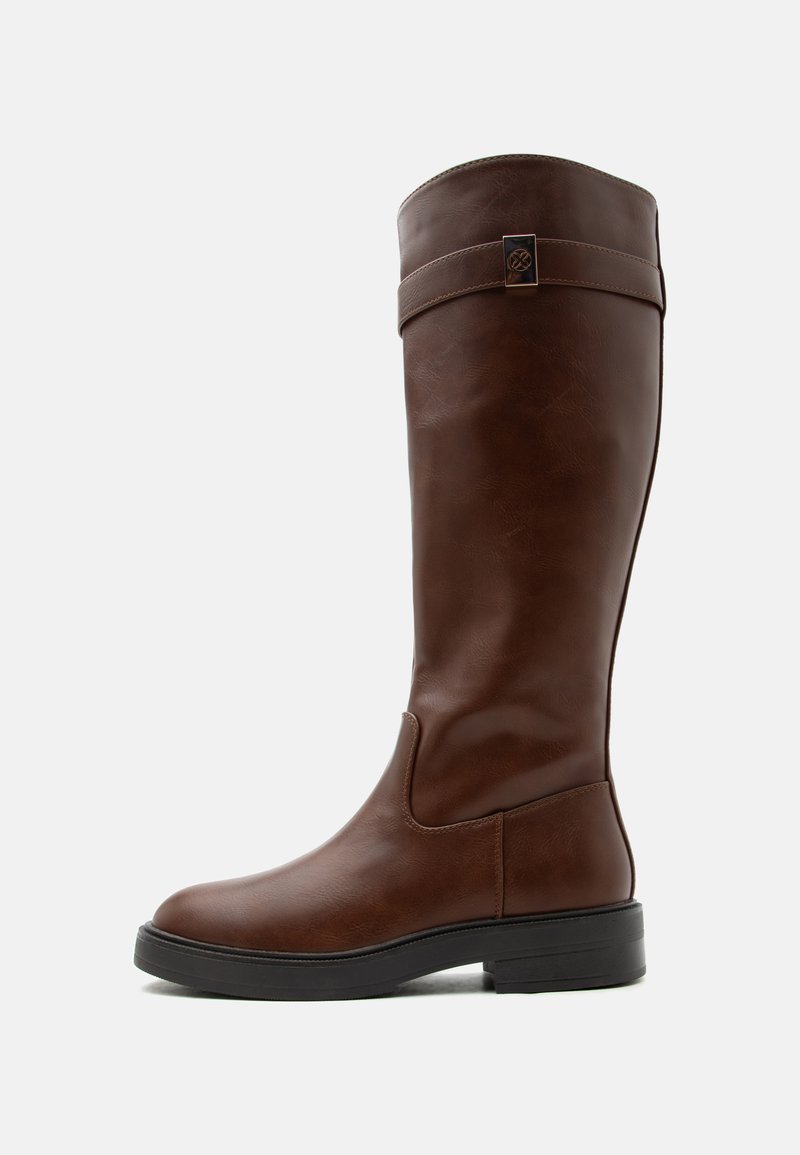 Botte en cuir marron montant jusqu'au genou avec semelle noire basse et sangle décorative avec emblème métallique près du haut.
