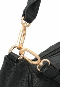Borsa nera in pelle sintetica con texture, dotata di accessori in oro, tra cui un grande moschettone e catene, e con chiusura superiore a zip.