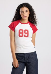 Cotton t-shirt with red raglan sleeves, white body, and a large red "89" printed on the front. Short sleeves and fitted design.