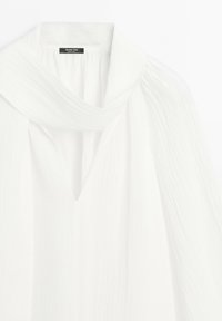 Witte blouse met lange mouwen met zachte plooien en een sjaalachtig kraagdetail, gemaakt van licht gestructureerde stof, Massimo Dutti merklabel zichtbaar.
