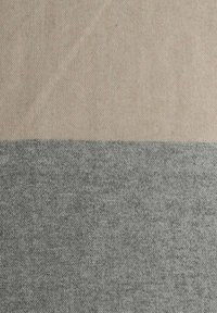 Textiel met een gladde textuur, met een tweekleurig ontwerp: beige bovenaan en donkergrijs eronder, met diagonale weefpatronen.