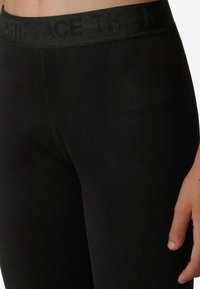 Svarta leggings med en bred, mörk midja med texten "THE NORTH FACE" i svart. Slät textur, tight passform.