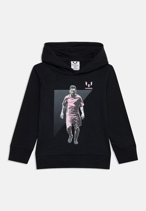 Čierna mikina s kapucňou s grafikou futbalistu kráčajúceho dopredu, oblečeného v uniforme, a slovom "Messi" s logom nad postavou.