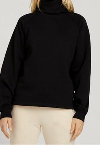 Černá roláková mikina s raglánovými rukávy, texturední tkaninou a žebrovanými manžetami. Navržena v uvolněném střihu a s minimálními detaily.