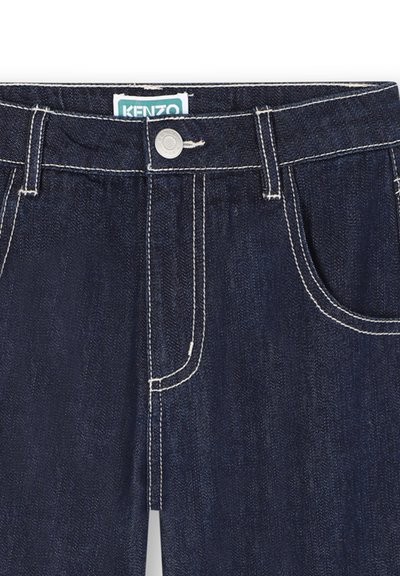 Jean en denim bleu marine avec des coutures blanches, cinq poches, une fermeture à bouton métallique et une étiquette à la taille portant la mention "KENZO."
