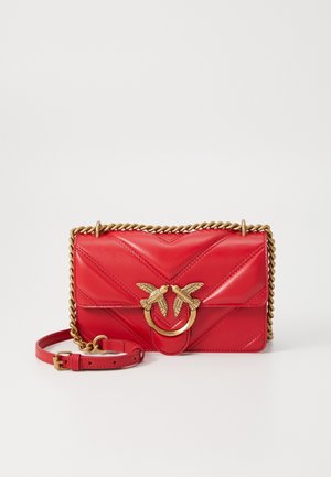 Sac bandoulière en cuir matelassé rouge avec bandoulière chaîne dorée et fermoir orné de deux oiseaux se faisant face.