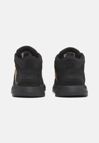 Černé a hnědé vysoké tenisky s texturovaným semišem a síťovaným svrškem, vybavené polstrovaným límcem a embosovaným logem "Timberland" na patě.