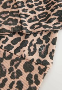 Tecană cu model de leopard în nuanțe de bej și negru, având o textură ribbed și un detaliu metalic cu logo. Trei straturi vizibile.