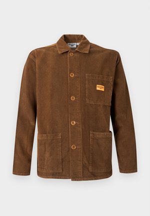 Brązowa kurtka sztruksowa z zapięciem na guziki, trzema dużymi kieszeniami oraz małą pomarańczową metką z logo na górnej lewej kieszeni.