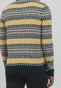 Strickpullover mit einem gemusterten Design in Gelb, Schwarz, Marineblau und Cremefarben. Gerippter Saum und Bündchen; geometrische Formen überall.