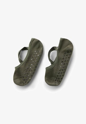 Paar olivgrüne Ballett-Grippsocken mit schwarzen rutschfesten Punkten und elastischen Riemen, flach auf einem weißen Hintergrund ausgelegt.