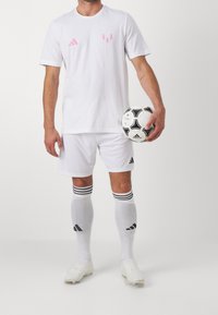 White soccer uniform with short sleeves, pink logo accents, black three-stripe patterns on socks, and a black and white soccer ball.