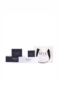 Scatole regalo assortite in bianco e nero, con "MYC PARIS" in alto rilievo argentato. Inclusa una borsa da shopping bianca con manici neri.