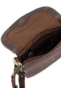 Brun lædertaske med tværrem og åben toplynlås, der viser det indvendige stoffor og metalspænde på den aftagelige rem.