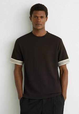 Bruin T-shirt met textuur, een ronde hals en korte mouwen. De mouwen hebben crèmekleurige horizontale strepen. Casual pasvorm met een rechte zoom.