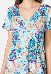 Abito a fantasia floreale in tessuto azzurro chiaro. Presenta una scollatura a V, maniche corte e una vita con cordoncino elastico, decorato con vivaci foglie tropicali e fiori.