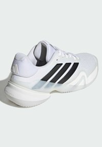 Biela športová obuv s priedušným sieťovinovým zvrškom, tromi čiernymi pruhmi a hrubou bielou podrážkou s priehľadným akcentom. Povrch s textúrovanými detailmi.