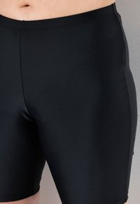 Shorts sportivi neri in tessuto morbido e elastico, con vestibilità aderente, vita elasticizzata e lunghezza a metà coscia. Senza fantasie né dettagli.