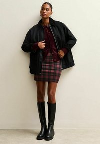 Black jacket, burgundy sweater, plaid mini skirt in red and black, and knee-high black boots. Smooth textures and fitted design.