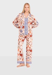 Floral-patterned, long-sleeve pajama set in light pink with red and blue accents. Features a collared shirt and wide-leg pants.