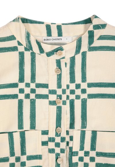 Chemise beige avec motif en grille géométrique verte, col rond, cinq boutons crème sur le devant et étiquette visible indiquant "BOBO CHOSES" taille S.