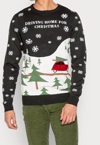 Maglione nero con fiocchi di neve bianchi, alberi verdi e un'auto rossa. Presenta il testo "DRIVING HOME FOR CHRISTMAS" in bianco sul petto.