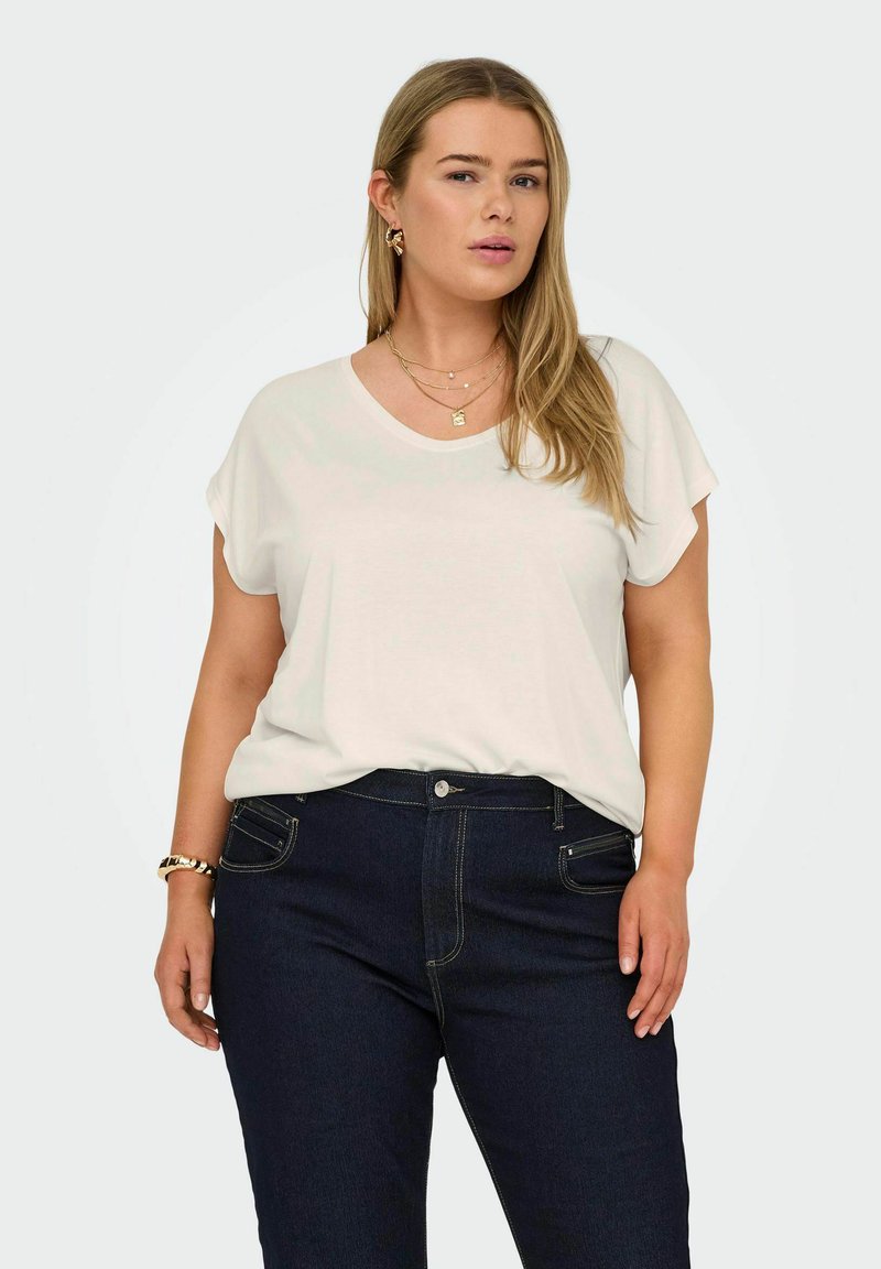 T-shirt blanc à manches courtes avec une coupe décontractée, associé à un jean en denim bleu foncé avec des coutures contrastantes et des poches avant.