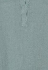 Light blue linen fabric with a close-up of a stitched placket detail at the neckline.
