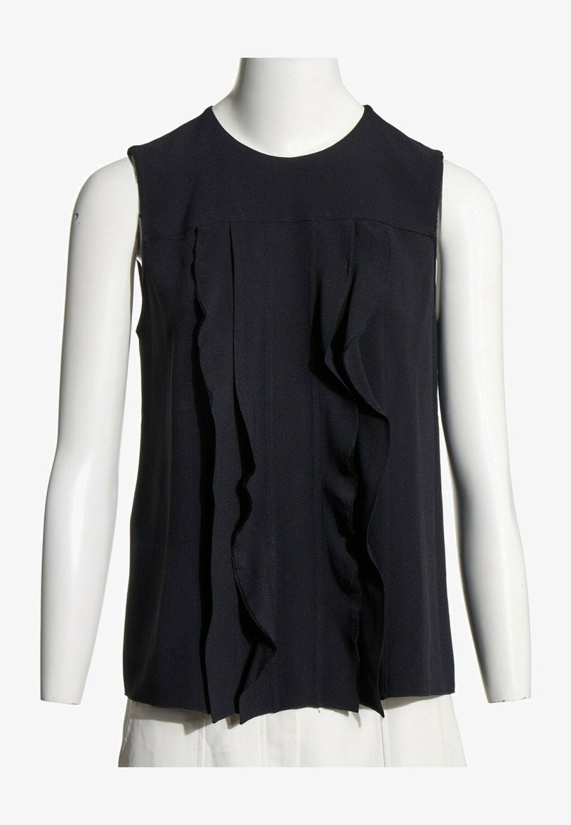 Blouse noire sans manches avec des détails de volants verticaux sur le devant, présentée sur un buste de mannequin blanc avec un fond blanc.