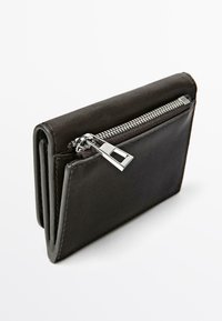 Portafoglio nero in pelle con scomparto con cerniera e ferramenta argentata. Caratterizzato da una texture liscia e un design compatto e pieghevole.