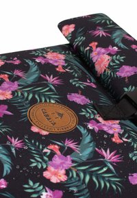 Sac à dos noir à fleurs avec des fleurs roses et violettes, des feuilles vertes, un tissu texturé, et un patch rond marron. Présente une pince noire.
