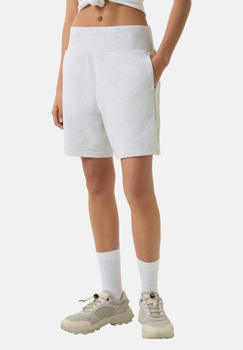 Gray cotton blend shorts with a wide waistband, side pockets, and contrasting side stripes. Worn with white socks and beige sneakers.