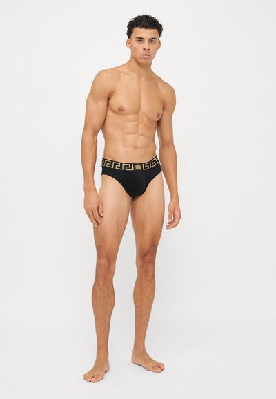 Shorts de bain noirs avec une ceinture à motif doré, présentant un ajustement snug et une texture lisse, conçus pour le confort et le style dans les environnements aquatiques.