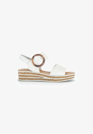Hvide kile sandaler med bred rem, cirkulært brunt accent og lagdelt korksål. Glat tekstur, åbent tådesign og justerbar hælrem.