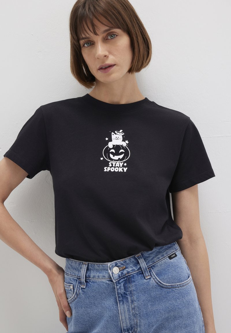 Black cotton t-shirt featuring a white graphic of a cat on a pumpkin with "STAY SPOOKY" text beneath. Relaxed fit and short sleeves.