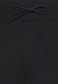 Zwarte sweatpants met een gladde textuur, voorzien van een trekkoord in de taille en een zak aan de voorkant. Eenvoudig ontwerp zonder zichtbare patronen of accenten.