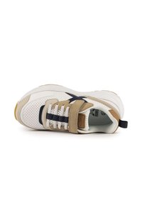 Baskets avec une tige en mesh blanc, des détails en daim beige et une sangle navy. Comprend une languette rembourrée et une semelle en caoutchouc marron. Détails texturés présents.