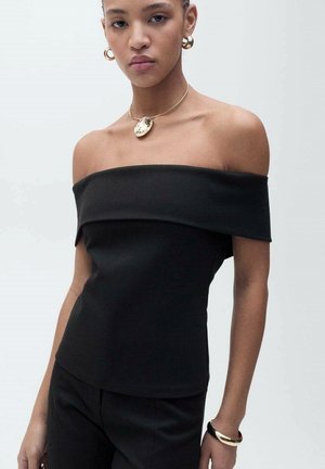 Black off-shoulder top made of solid fabric. Smooth texture with a fitted shape. Worn with gold circular necklace and hoop earrings.