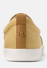 Tan vävd sneaker med en texturerad yta, vit sula och en hälla i brunt läder som har en guldfärgad "RL" logotyp som accent.