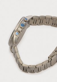 Hopeakylkinen kello, jossa on pyöreä kuori, kolme sinistä painiketta ja teksturoitu metalliranneke, jossa on suorakaiteen muotoisia linkkejä.