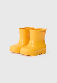 Bottes de cheville en caoutchouc jaunes avec une finition lisse, des bouts arrondis et une semelle texturée pour une meilleure adhérence. La marque est embossée sur le côté.