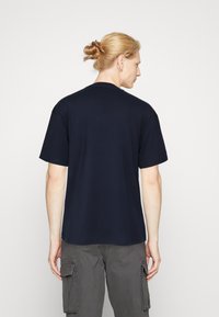 Camiseta de algodón azul marino con mangas cortas, escote redondo y un corte relajado. Diseño minimalista, sin patrones ni logotipos visibles.