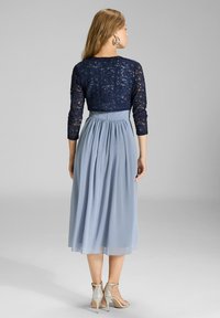 Granatowy koronkowy gorset z rękawami o długości trzech czwartych, zwiewna jasnoniebieska sukienka z szyfonu oraz jasnosrebrne obcasy.